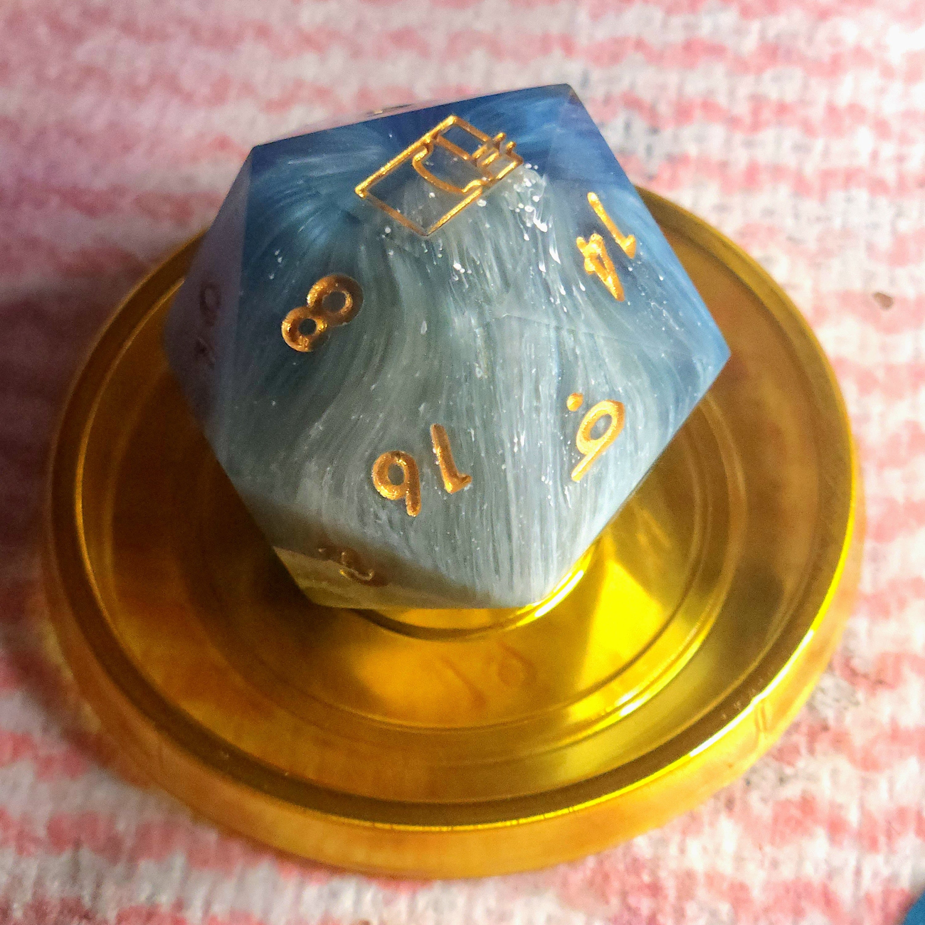 Polyhedral dice with gold numbers on a pink checkered background